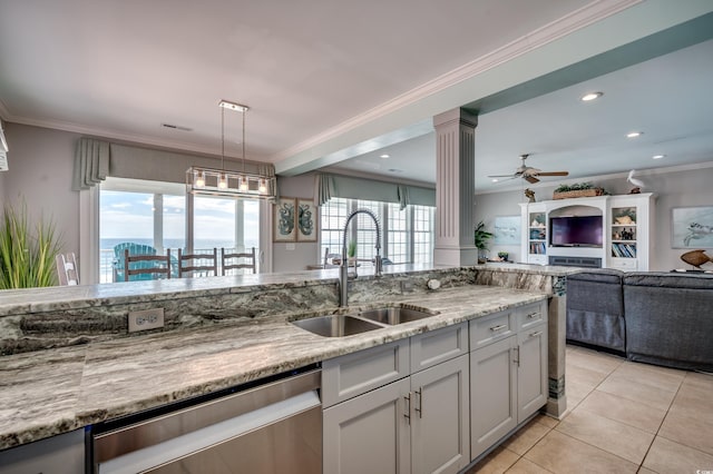 kitchen featuring light stone countertops, a healthy amount of sunlight, sink, and decorative columns