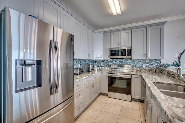 kitchen featuring sink, ornamental molding, gray cabinets, light stone countertops, and appliances with stainless steel finishes