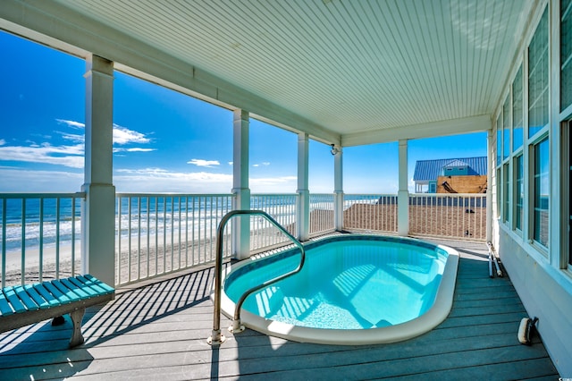 view of swimming pool featuring a view of the beach and a water view