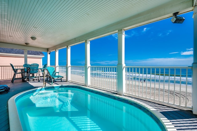 view of swimming pool with a beach view and a water view