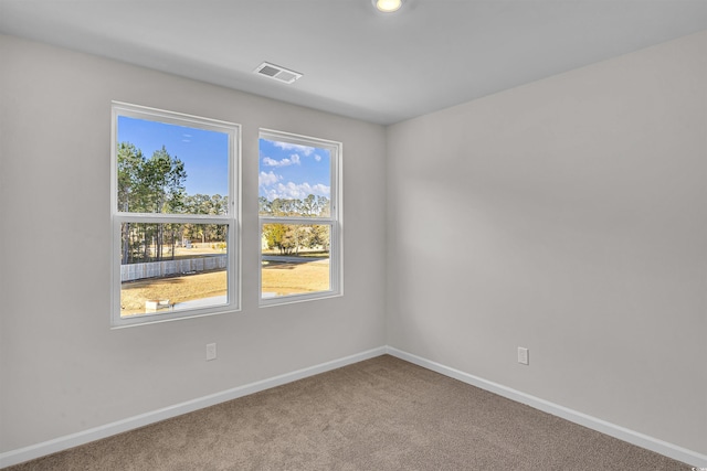 empty room with baseboards, carpet flooring, a healthy amount of sunlight, and visible vents