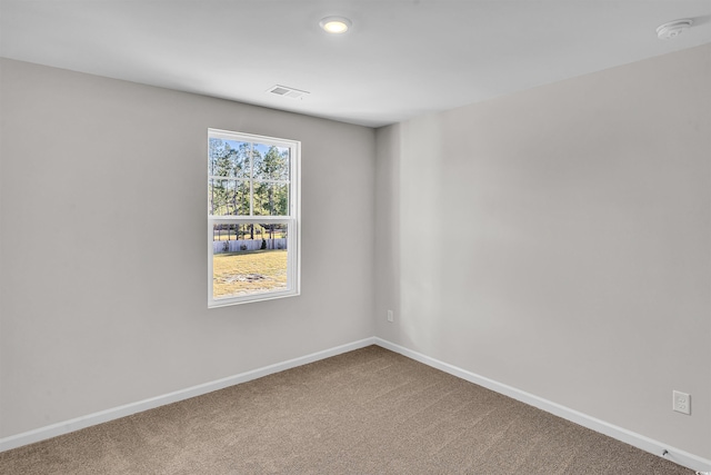 carpeted spare room with visible vents and baseboards