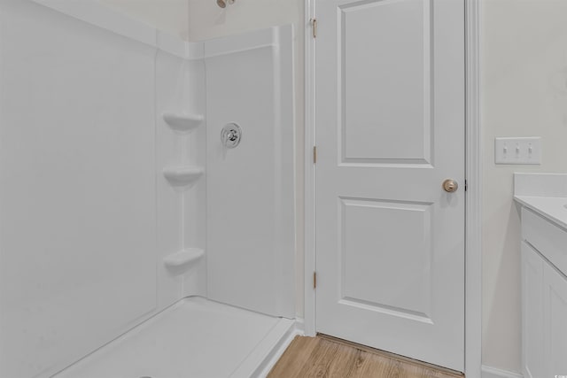 full bath featuring vanity, wood finished floors, and a shower
