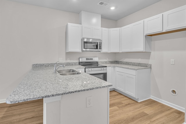 kitchen featuring visible vents, appliances with stainless steel finishes, light stone countertops, a sink, and a peninsula