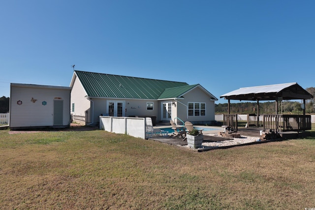 rear view of house with a gazebo, a swimming pool side deck, a patio area, a shed, and a lawn