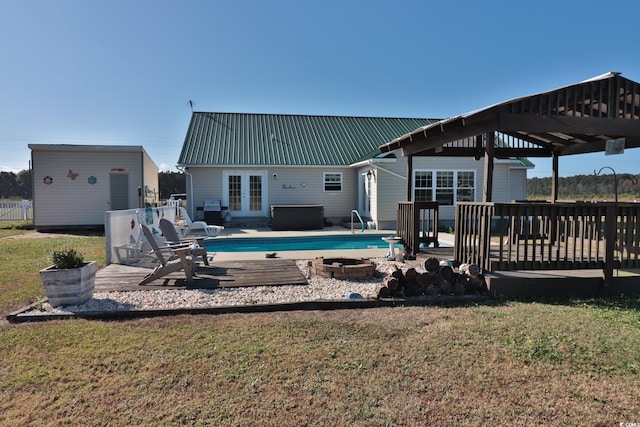 rear view of property featuring a lawn, french doors, a deck, and an outdoor fire pit