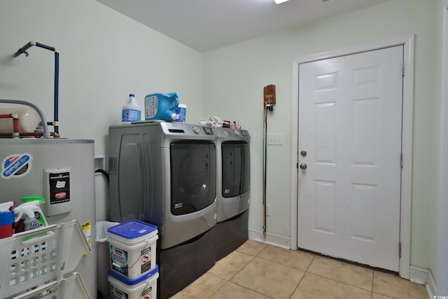 laundry room with electric water heater, washer and clothes dryer, and light tile patterned floors