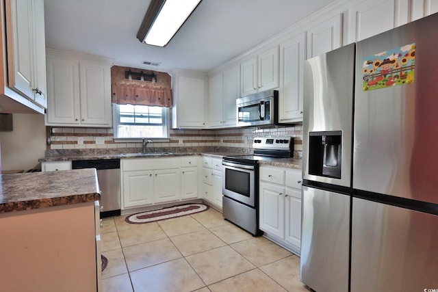 kitchen with white cabinets, appliances with stainless steel finishes, light tile patterned floors, and sink