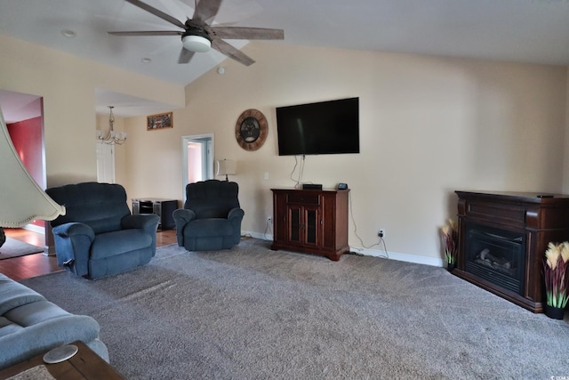 carpeted living room featuring ceiling fan with notable chandelier and vaulted ceiling