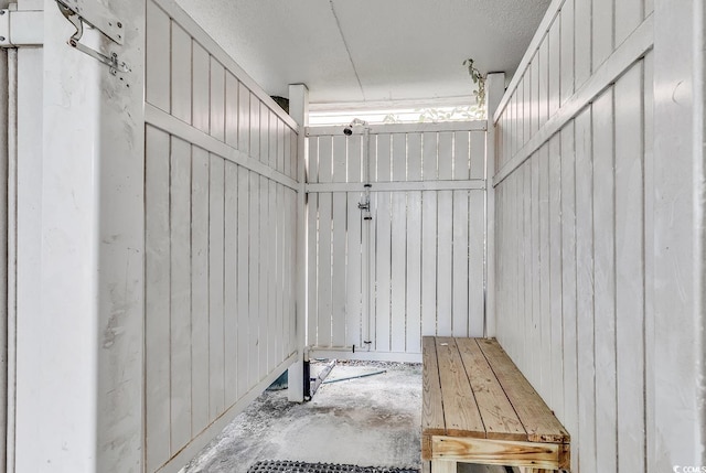 mudroom featuring concrete flooring and wooden walls