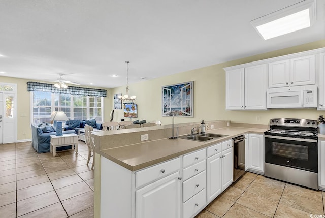 kitchen with sink, kitchen peninsula, appliances with stainless steel finishes, white cabinets, and pendant lighting