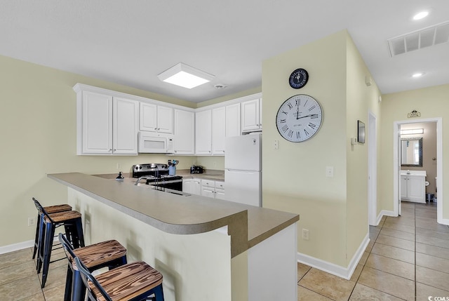 kitchen with kitchen peninsula, sink, a breakfast bar, white cabinetry, and white appliances