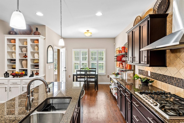 kitchen with stainless steel appliances, dark brown cabinets, sink, dark wood-type flooring, and wall chimney exhaust hood