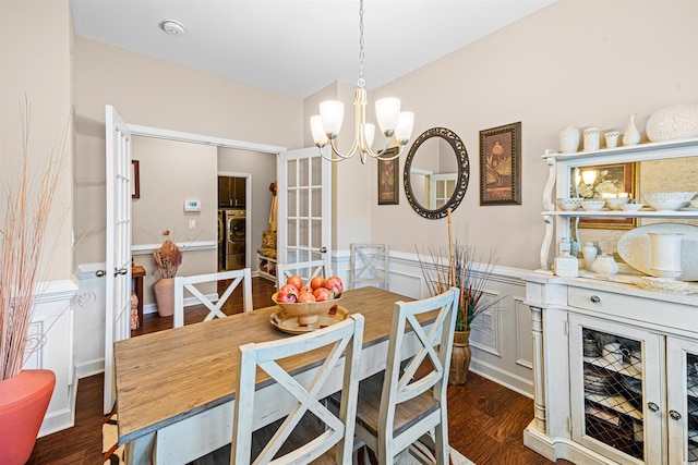 dining space featuring dark wood-type flooring, an inviting chandelier, and washer / dryer