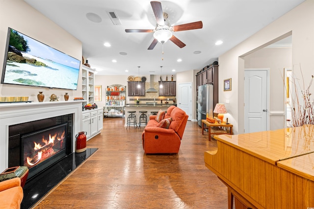 living room featuring a premium fireplace, dark hardwood / wood-style floors, ceiling fan, and sink