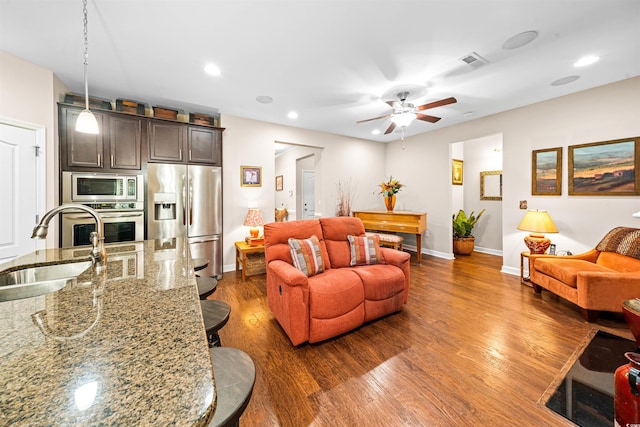 living room featuring dark wood-type flooring, sink, and ceiling fan