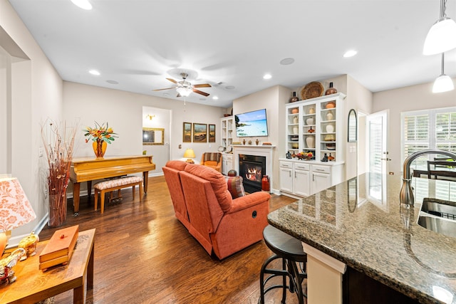 living room featuring ceiling fan, sink, and dark hardwood / wood-style flooring