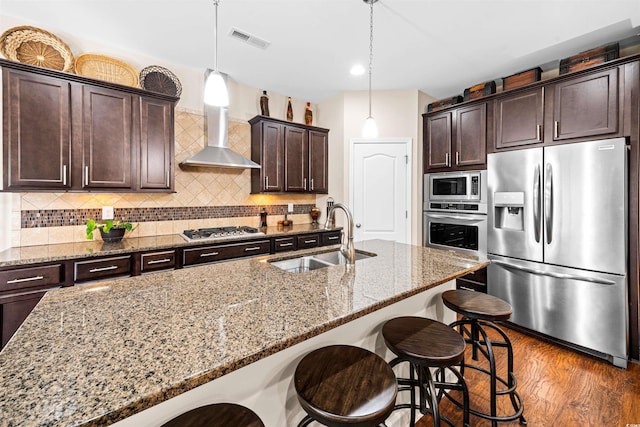 kitchen with light stone counters, appliances with stainless steel finishes, dark hardwood / wood-style floors, hanging light fixtures, and sink