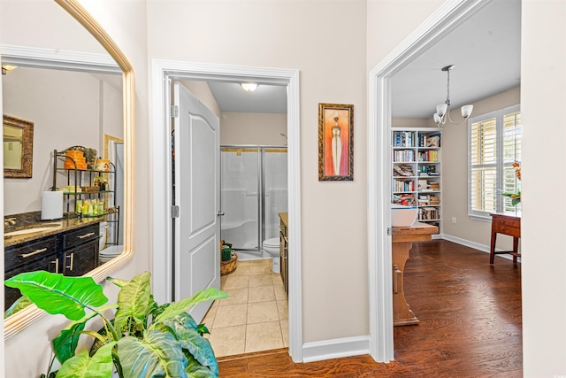 corridor with wood-type flooring, sink, and a notable chandelier