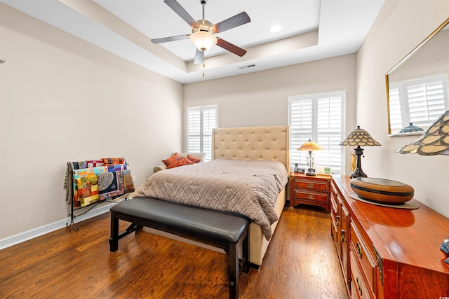 bedroom featuring a raised ceiling, ceiling fan, and dark hardwood / wood-style floors