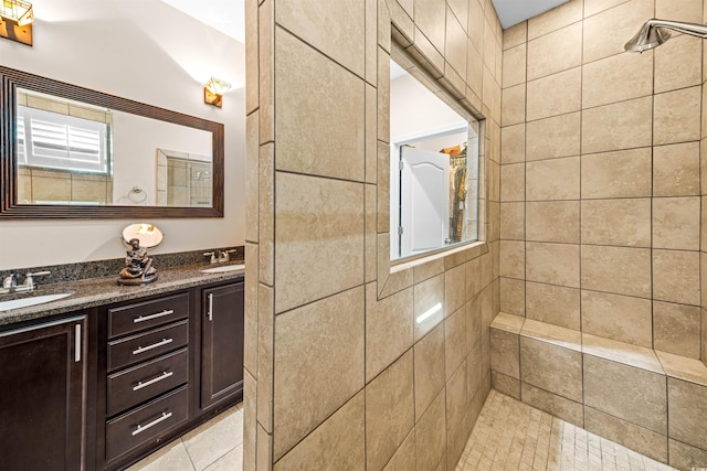 bathroom featuring tile patterned flooring, vanity, and a tile shower