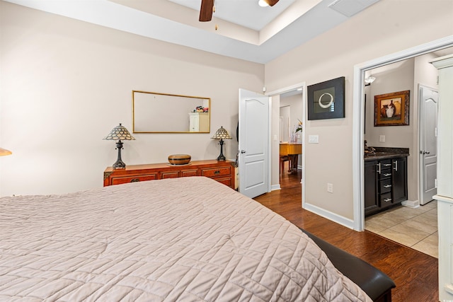 bedroom with ceiling fan, connected bathroom, and light hardwood / wood-style flooring