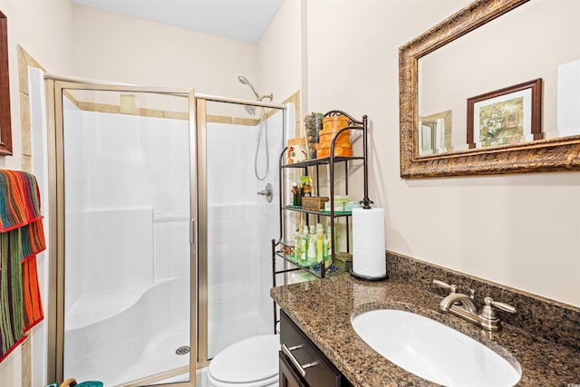 bathroom featuring toilet, vanity, and a shower with door