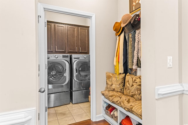 laundry room with washing machine and dryer, cabinets, and light tile patterned floors