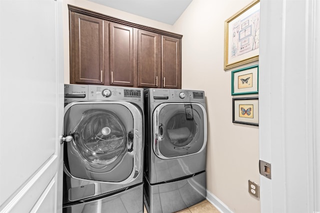 laundry area with cabinets, independent washer and dryer, and light tile patterned flooring