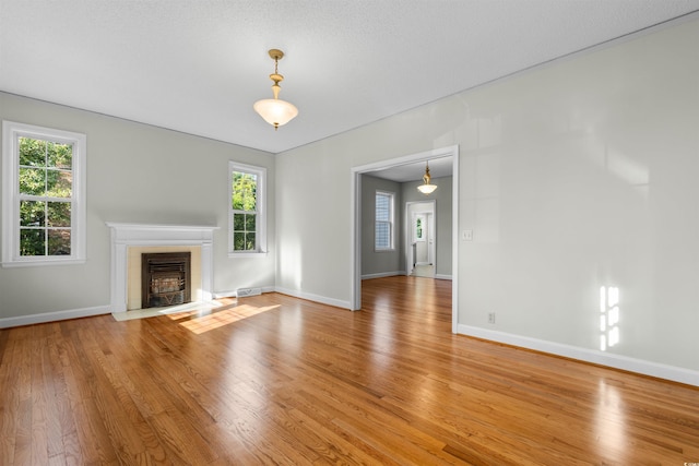 unfurnished living room featuring light wood finished floors, baseboards, and a tiled fireplace