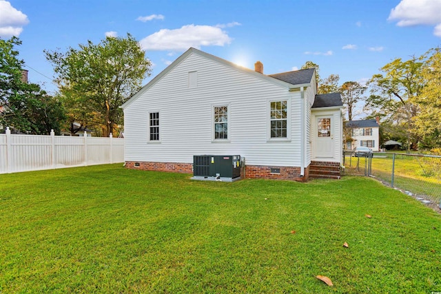 back of house with entry steps, a lawn, a fenced backyard, crawl space, and central air condition unit