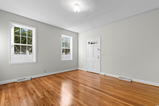 spare room featuring a textured ceiling, wood-type flooring, and visible vents