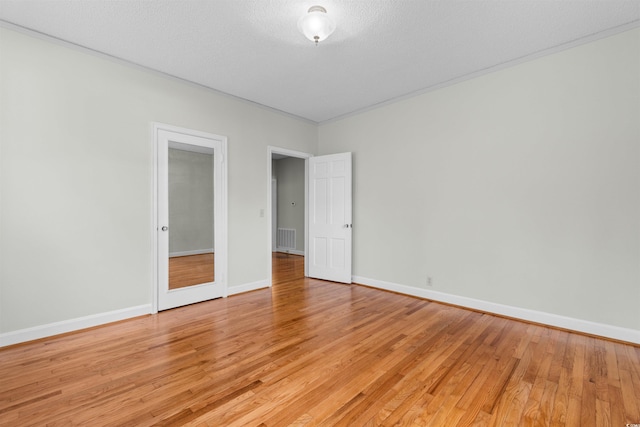 unfurnished bedroom with light wood finished floors, visible vents, baseboards, and a textured ceiling