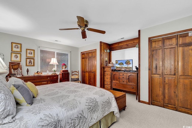 carpeted bedroom with multiple closets and ceiling fan