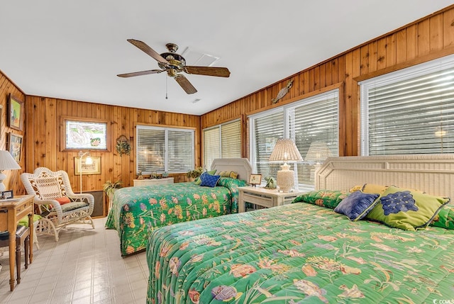 bedroom featuring wood walls, ceiling fan, and multiple windows