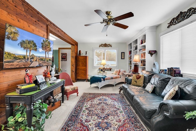 living room featuring ceiling fan, wooden walls, and light colored carpet