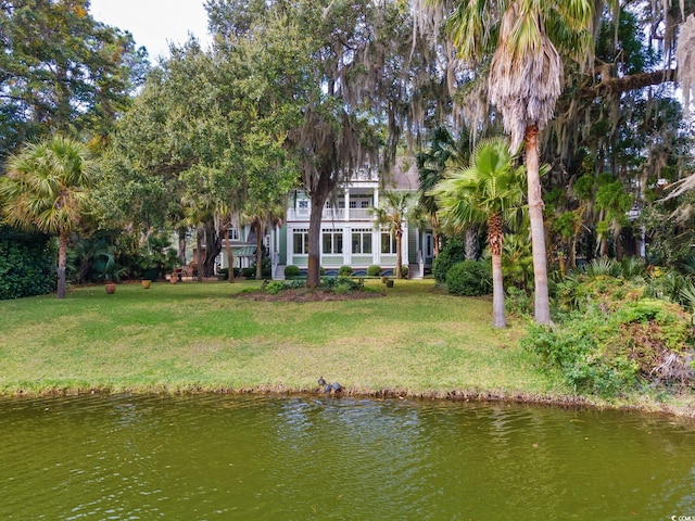 rear view of property featuring a water view and a lawn