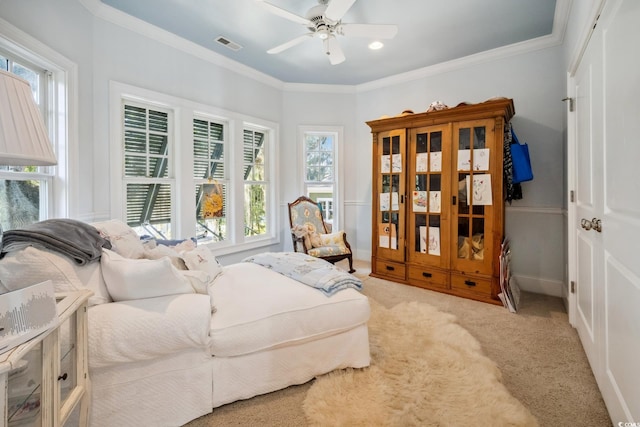 living area featuring ceiling fan, a wealth of natural light, light colored carpet, and ornamental molding