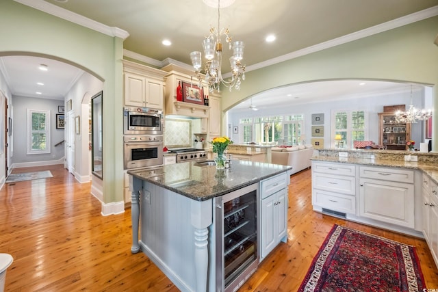 kitchen featuring dark stone countertops, beverage cooler, hanging light fixtures, and light hardwood / wood-style flooring