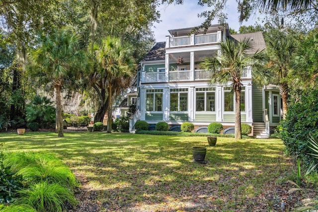 rear view of house with a yard and a balcony