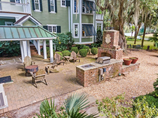 view of patio with a fireplace, a fire pit, and a balcony