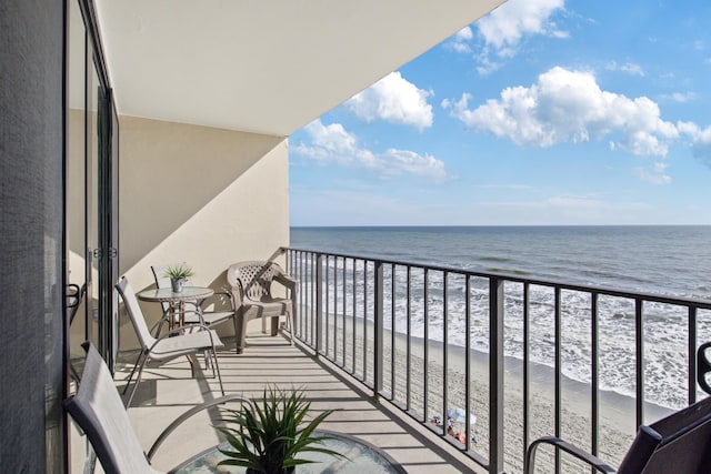 balcony featuring a view of the beach and a water view