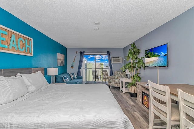 1207 S Ocean Blvd Unit 51408, Myrtle Beach, SC 29577 - bedroom with wood finished floors, access to exterior, a textured ceiling, an AC wall unit, and a glass covered fireplace