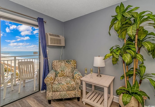 1207 S Ocean Blvd Unit 51408, Myrtle Beach, SC 29577 - living area with wood finished floors, view of water and beach, a textured ceiling, and a wall mounted air conditioner