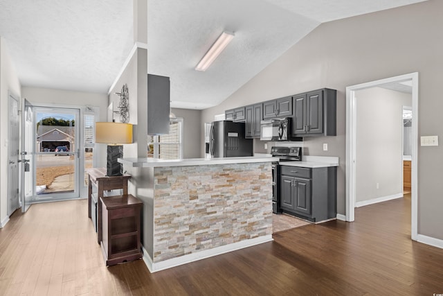 kitchen with stainless steel appliances, wood finished floors, gray cabinets, and light countertops