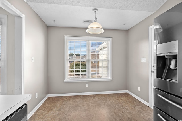 unfurnished dining area with visible vents, baseboards, and a textured ceiling