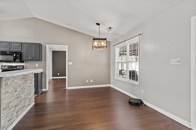 kitchen with dark wood finished floors, stove, vaulted ceiling, light countertops, and black microwave