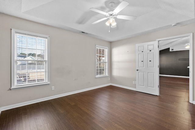 unfurnished room with dark wood-type flooring, a wealth of natural light, visible vents, and baseboards