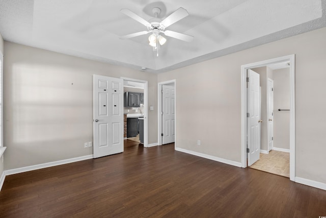 empty room with dark wood-style floors, ceiling fan, and baseboards