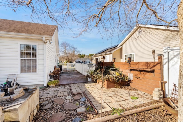 exterior space featuring fence, a wooden deck, and a patio